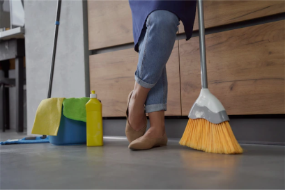 A woman is sweeping the floor with her feet.
