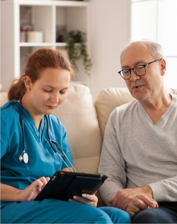 A nurse and an older man looking at a tablet.
